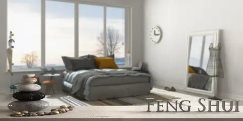 Une chambre apaisante avec un lit douillet, une pile de galets et le mot "FENG SHUI" en lettres métalliques.