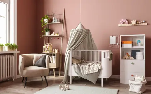 Une chambre bébé DIY chaleureuse avec un lit blanc, un fauteuil confortable, une étagère murale décorée et des jouets en bois.