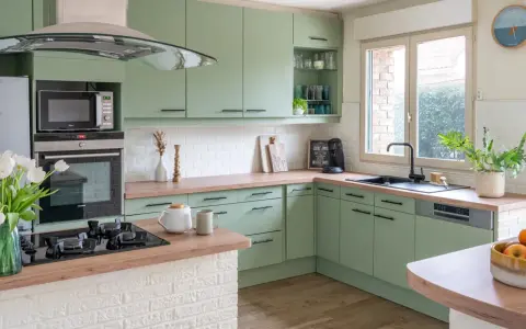 Cuisine vert d'eau et bois, avec des armoires douces, un plan de travail en bois chaleureux et des touches de blanc. Un espace invitant pour cuisiner et partager.