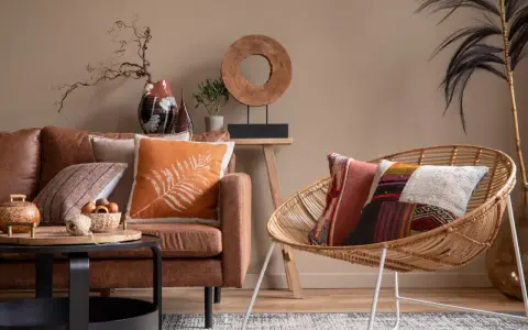 Salon chaleureux avec canapé en cuir marron, coussins colorés et fauteuil en rotin. Une belle idee deco interieur pour une ambiance cosy.