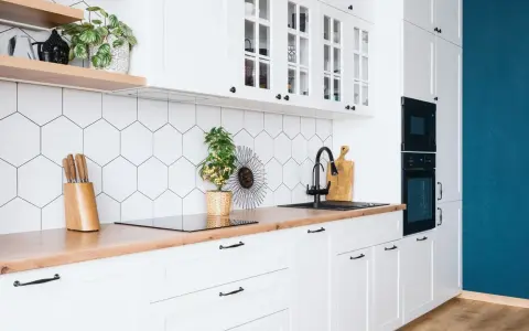 Cuisine moderne et lumineuse avec carrelage hexagonal blanc, plan de travail en bois et meubles blancs. Idéal pour refaire sa cuisine petit budget.