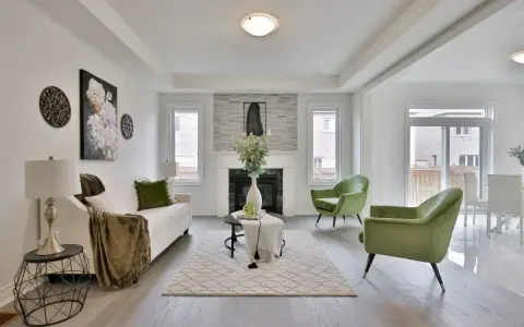 Salon moderne avec canapé blanc, fauteuils verts et cheminée. Idéal pour un conseil décoration intérieur gratuit.