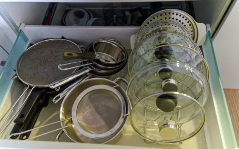 Tiroir de cuisine bien organisé avec une astuce pour ranger les couvercles de casseroles et poêles en verre et métal.