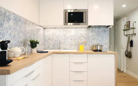 Cuisine moderne avec crédence carrelée bleu et blanc, plans de travail en bois et meubles blancs. Une idée pour une crédence cuisine blanche et originale.
