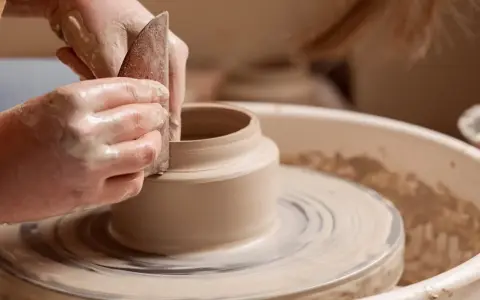 Mains argileuses façonnant un vase sur un tour, une scène d'inspiration peinture céramique.