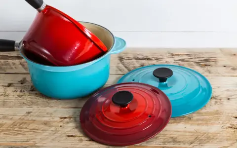 Une astuce rangement casserolier : une cocotte bleue empilée avec une rouge à l'intérieur, et deux couvercles colorés à côté.