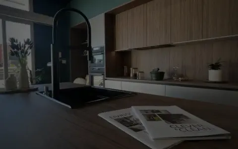 Cuisine moderne avec îlot central, robinetterie noire et magazines sur le plan de travail. Idéal pour rénover une cuisine.