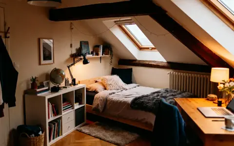 Chambre sous comble très bas, avec lit douillet, bureau et étagères. Lumière tamisée par les lucarnes et guirlandes.