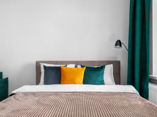 Lit de chambre cabine avec coussins colorés et rideaux verts.