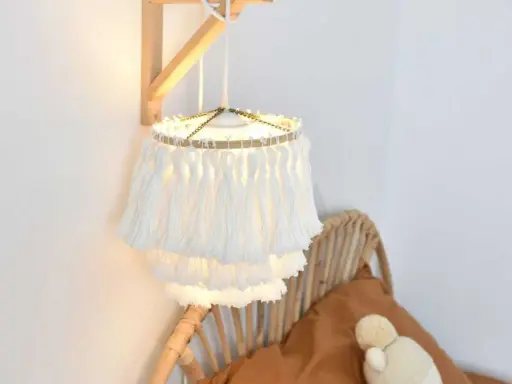 Un abat jour DIY en macramé blanc, avec des franges douces, éclaire une chambre cosy.