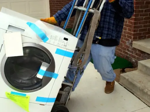 Un homme utilise un chariot pour comment monter une machine à laver dans les escaliers.