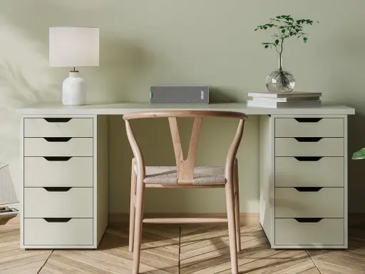 Un bureau DIY épuré avec une chaise en bois, une lampe, un haut-parleur et une plante.