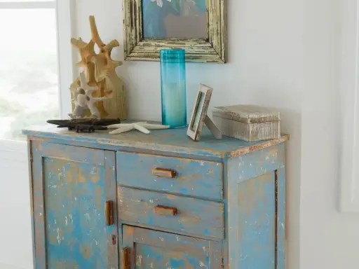 Meuble patiné bleu délavé, orné d'objets marins et d'une boîte décorative.