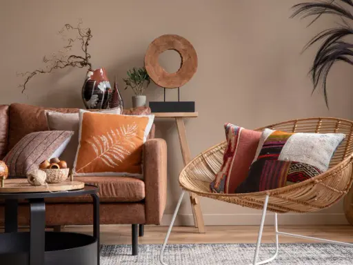 Salon chaleureux avec canapé en cuir marron, coussins colorés et fauteuil en rotin. Une belle idee deco interieur pour une ambiance cosy.