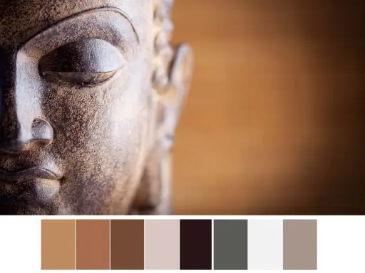 Gros plan sur le visage d'une statue de Bouddha aux tons terreux, avec une palette de couleurs apaisantes.
