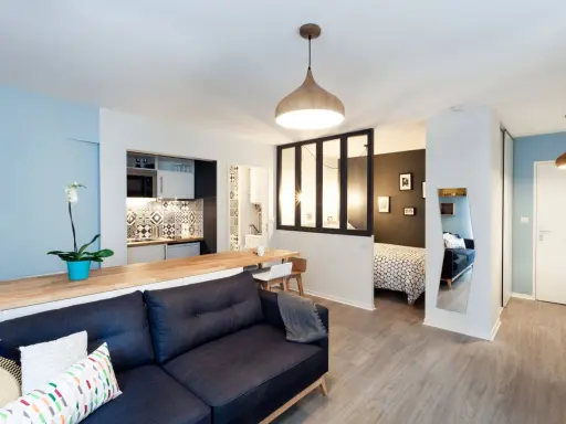 Aménagement studio 30m2 : salon cosy, cuisine moderne, coin repas et chambre séparée par une verrière.