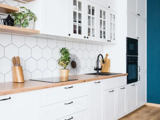 Cuisine moderne et lumineuse avec carrelage hexagonal blanc, plan de travail en bois et meubles blancs. Idéal pour refaire sa cuisine petit budget.