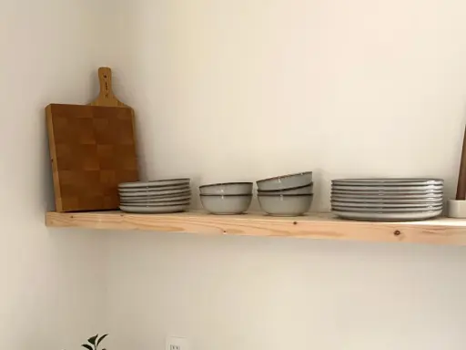 Étagère en bois brut, parfaite pour une cuisine de style **diy etagere bois**. Elle accueille une planche à découper, des assiettes, des bols et des bougies.
