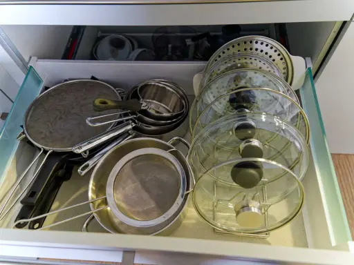Tiroir de cuisine bien organisé avec une astuce pour ranger les couvercles de casseroles et poêles en verre et métal.