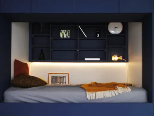 Un lit confortable dans une alcôve bleue, avec des étagères remplies d'objets décoratifs. Parfait pour refaire sa chambre avec style.