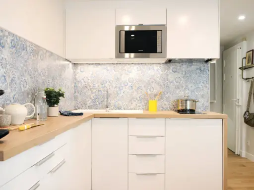 Cuisine moderne avec crédence carrelée bleu et blanc, plans de travail en bois et meubles blancs. Une idée pour une crédence cuisine blanche et originale.