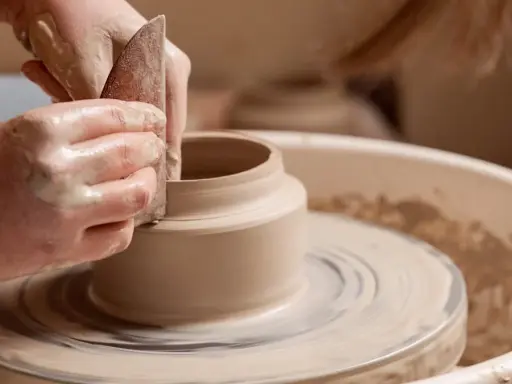Mains argileuses façonnant un vase sur un tour, une scène d'inspiration peinture céramique.