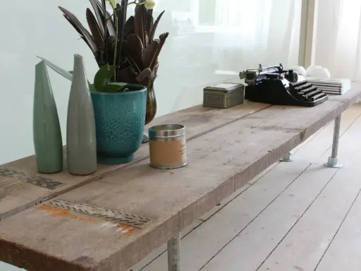 Une table basse rustique, idéale pour savoir que faire avec des vieilles planches de bois. Elle est décorée d'une machine à écrire vintage, de vases et d'une bougie.