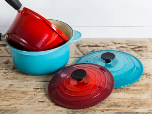 Une astuce rangement casserolier : une cocotte bleue empilée avec une rouge à l'intérieur, et deux couvercles colorés à côté.