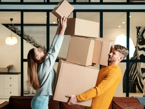 Couple jonglant avec des cartons. Difficile de savoir combien de cartons pour un déménagement quand on est aussi désorganisé !