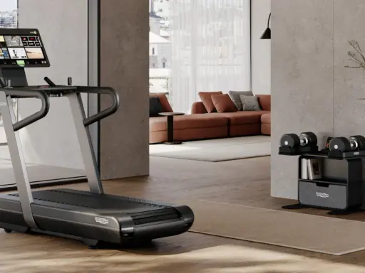 Un tapis de course et des haltères ajustables pour faire une salle de sport chez soi. Un espace moderne et fonctionnel pour le fitness à domicile.