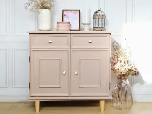 Meuble bas rose poudré, prêt à repeindre, avec deux tiroirs et deux portes. Décoré de fleurs séchées et d'une cage ornementale.
