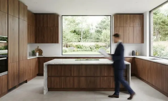 Cuisine moderne en 2 parties, avec des armoires en bois de noyer et un îlot central en marbre. Une grande fenêtre donne sur un jardin luxuriant.