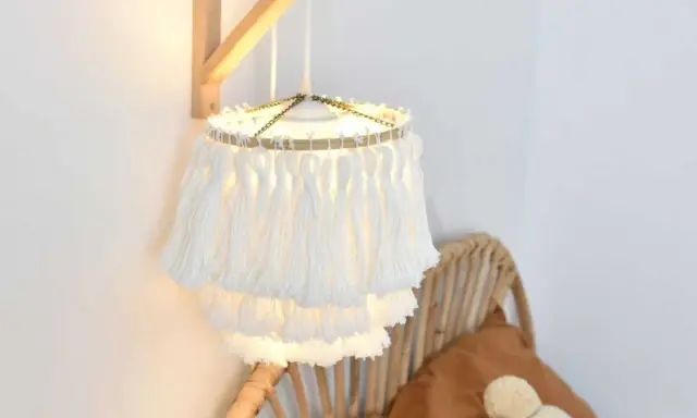Un abat jour DIY en macramé blanc, avec des franges douces, éclaire une chambre cosy.