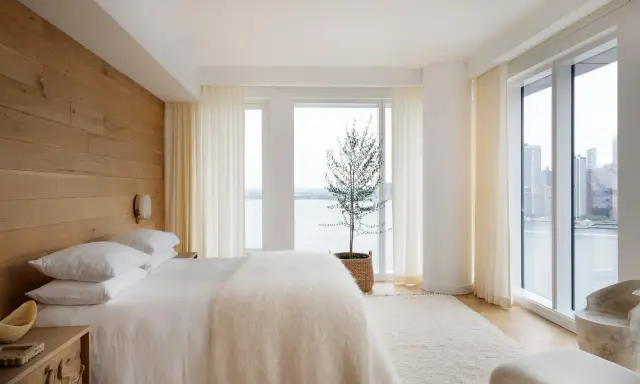 Une chambre à coucher simple et moderne avec un mur en bois, un lit blanc douillet et une vue imprenable sur la ville et l'eau.