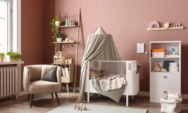 Une chambre bébé DIY chaleureuse avec un lit blanc, un fauteuil confortable, une étagère murale décorée et des jouets en bois.