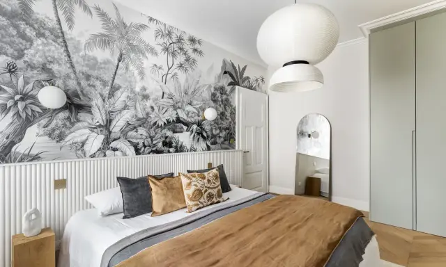 Tête de lit peinture graphique d'une jungle luxuriante en noir et blanc, créant une ambiance tropicale.