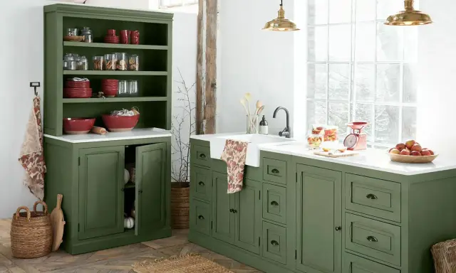 Ambiance rustique pour cette rénovation vieille cuisine. Meubles verts, vaisselle rouge, et lumière naturelle.