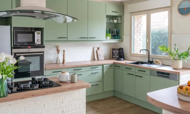 Cuisine vert d'eau et bois, avec des armoires douces, un plan de travail en bois chaleureux et des touches de blanc. Un espace invitant pour cuisiner et partager.