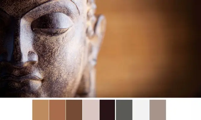 Gros plan sur le visage d'une statue de Bouddha aux tons terreux, avec une palette de couleurs apaisantes.