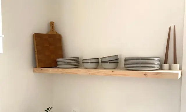 Étagère en bois brut, parfaite pour une cuisine de style **diy etagere bois**. Elle accueille une planche à découper, des assiettes, des bols et des bougies.
