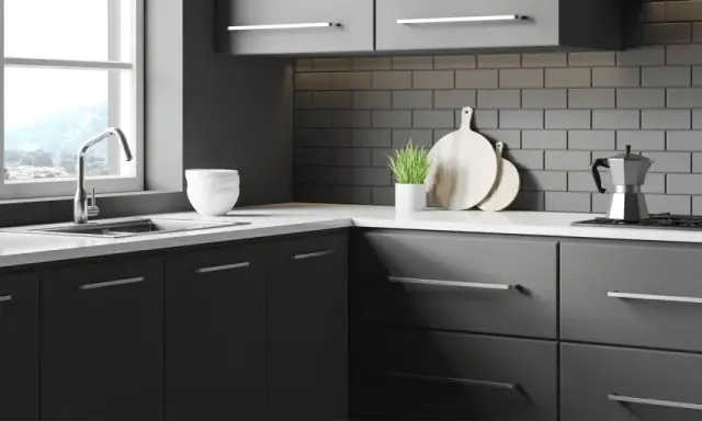 Cuisine moderne avec meubles gris foncés, carrelage métro anthracite et plan de travail blanc. Idéal pour un projet de renover meuble cuisine.