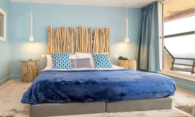 Tête de lit bois à faire soi-même, ambiance bord de mer avec coussins bleus et couverture marine.