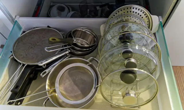 Tiroir de cuisine bien organisé avec une astuce pour ranger les couvercles de casseroles et poêles en verre et métal.