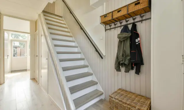 Escalier blanc et gris, avec des marches en bois clair. Une idée pour peindre une cage d'escalier quelle couleur ? Ce style épuré est très tendance.
