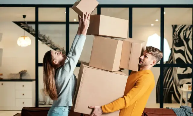 Couple jonglant avec des cartons. Difficile de savoir combien de cartons pour un déménagement quand on est aussi désorganisé !