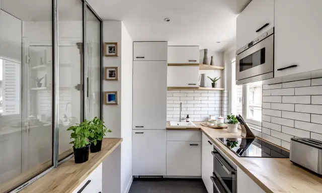 Plan d'une petite cuisine en U moderne et lumineuse, avec des placards blancs, un plan de travail en bois et un carrelage métro.