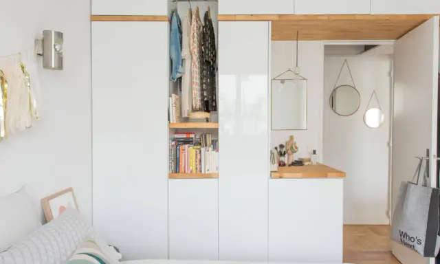 Chambre avec dressing intégré, organisée avec des étagères de livres et des vêtements suspendus. Un coin coiffeuse avec miroir et accessoires complète l'espace.