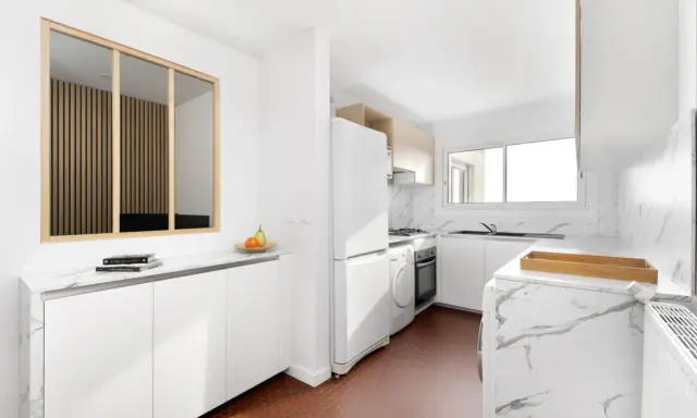 Relooker cuisine avant après : une cuisine moderne et lumineuse avec des meubles blancs, un plan de travail marbré et un sol hexagonal rouge.