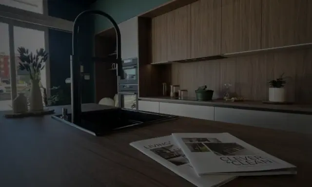 Cuisine moderne avec îlot central, robinetterie noire et magazines sur le plan de travail. Idéal pour rénover une cuisine.