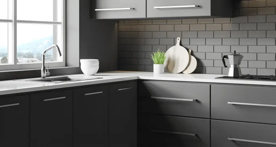 Cuisine moderne avec meubles gris foncés, carrelage métro anthracite et plan de travail blanc. Idéal pour un projet de renover meuble cuisine.